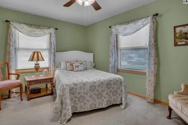 This bedroom features a bed, nightstand, chair, and a ceiling fan.