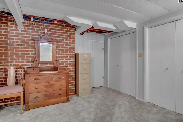 This room features exposed ceiling beams, a brick accent wall, and two large closets.