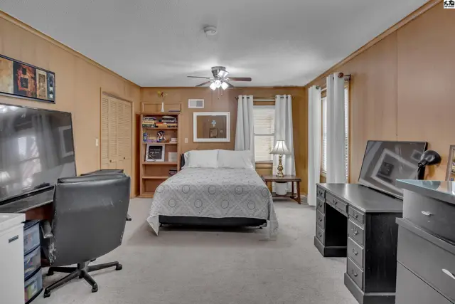 This bedroom features a ceiling fan, built-in shelving, and carpeted floors.