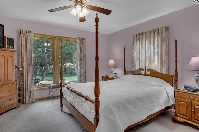 Spacious bedroom features a four-poster bed, plush carpet, and large window.