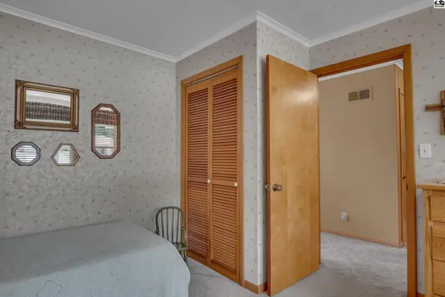 This room features a bed, louvered closet doors, and decorative mirrors.