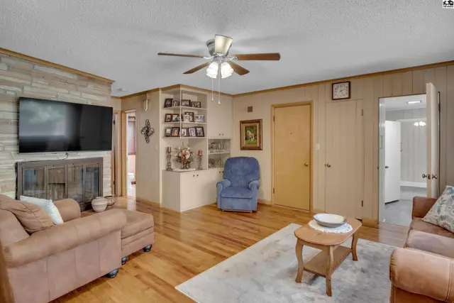 Spacious living room with a stone fireplace, built-in shelving, and wood-paneled walls.