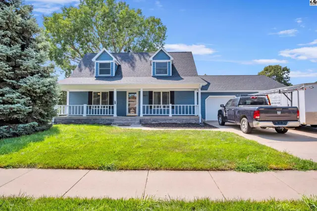 Blue siding house with a white porch, attached garage, and green lawn.