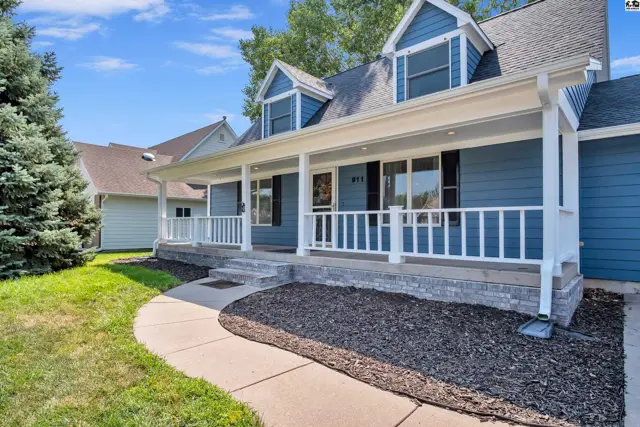 Blue siding home features a covered front porch with white railings and a stone foundation.