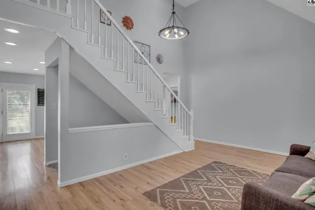 Spacious foyer with a vaulted ceiling, light wood flooring, and a white staircase.