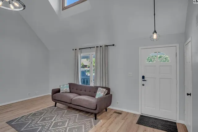 Spacious living area with vaulted ceiling, skylight, and wood-look flooring.