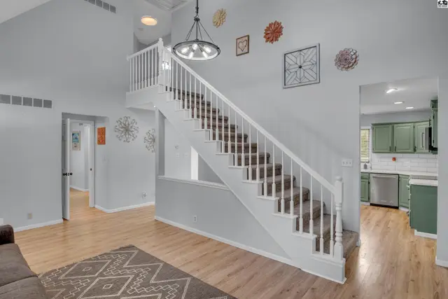 A white staircase with carpeted treads ascends to the upper level of this home.