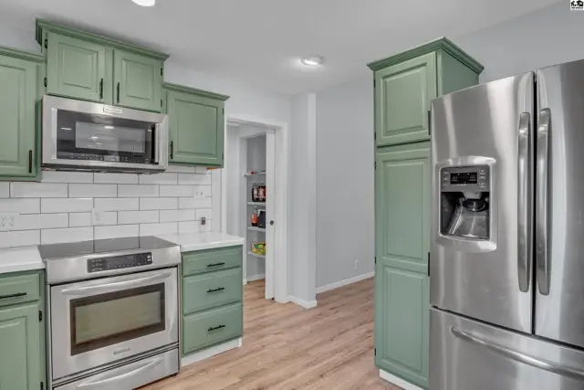 Kitchen features sage green cabinets, stainless steel appliances, and subway tile backsplash.