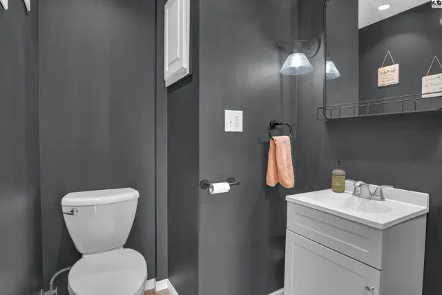 This bathroom features a white toilet, vanity, and a mirrored medicine cabinet.