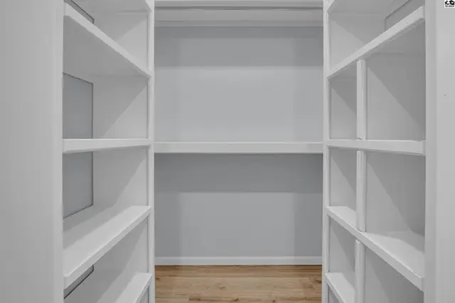 This room features floor-to-ceiling white shelving units and light wood flooring.