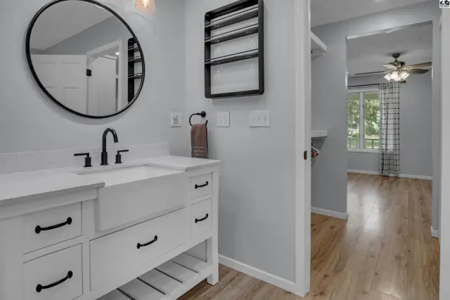 Modern bathroom with a white vanity, large sink, and a circular mirror.