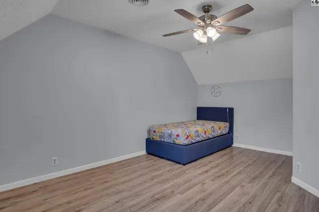 This room features light grey walls, a ceiling fan, and wood-look flooring.