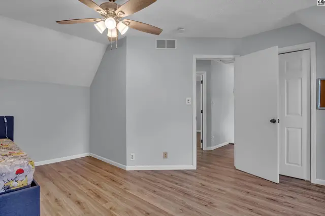 This room features light gray walls, wood-look flooring, and a ceiling fan.