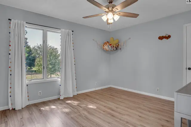 This room features light blue walls, a ceiling fan, and wood-look flooring.