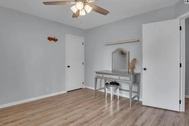 This room features light grey walls, a ceiling fan, and light wood-look flooring.
