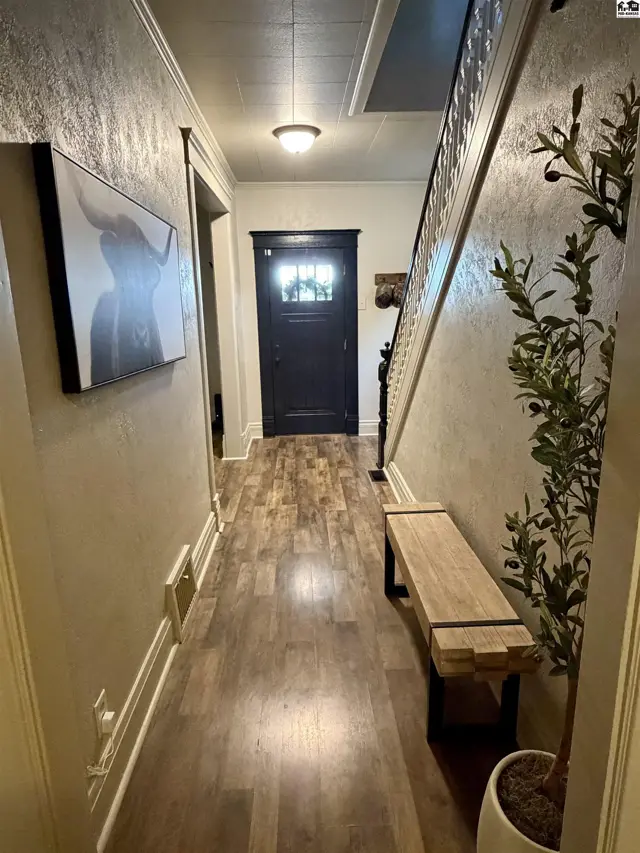 Hallway with wood-look flooring, a dark front door, and a bench.