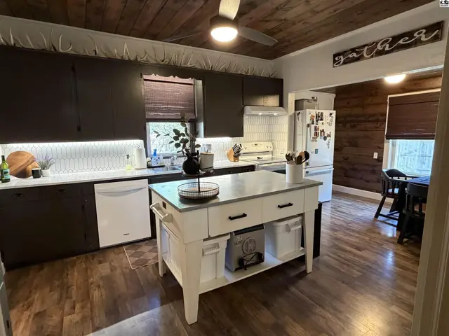 Spacious kitchen features dark cabinetry, white countertops, and a central island.