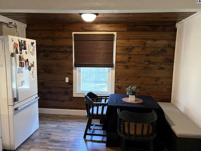 This kitchen features wood-paneled walls, a built-in bench, and a window with a woven shade.