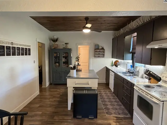 Spacious kitchen features dark cabinetry, a central island, and a wood-paneled ceiling.