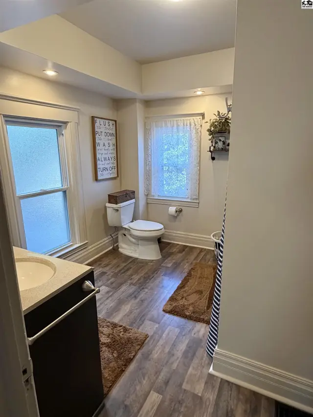 This bathroom features a vanity, toilet, and a shower with a striped curtain.