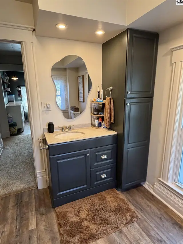 Dark grey vanity with a light countertop and a tall cabinet next to it.