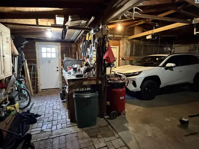 This garage features a workbench, storage cabinets, and a white SUV.