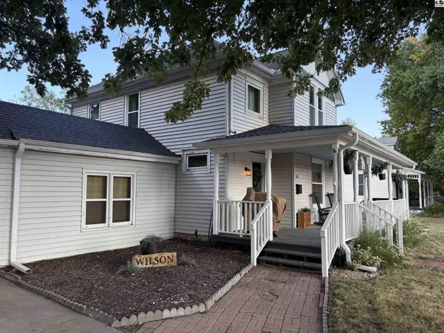 White vinyl siding covers this two-story home with a covered front porch and white railings.
