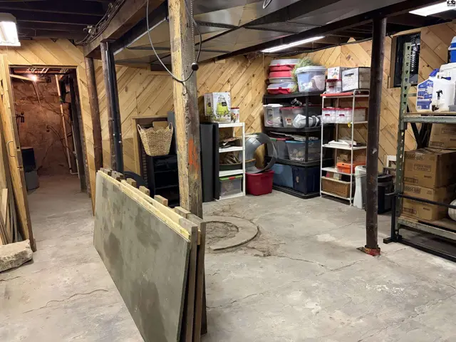 This unfinished basement features wood-paneled walls, concrete floors, and exposed support beams.