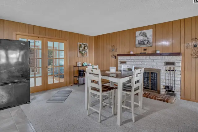Wood-paneled walls frame a dining area with a fireplace and glass doors.