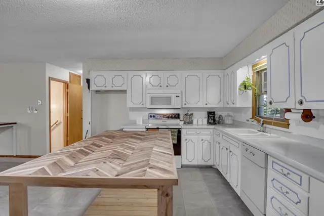 Spacious kitchen features white cabinetry, a large island, and ample counter space.