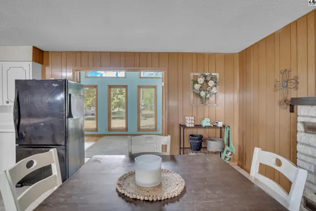 Wood-paneled walls and a dark dining table with chairs are featured in this room.