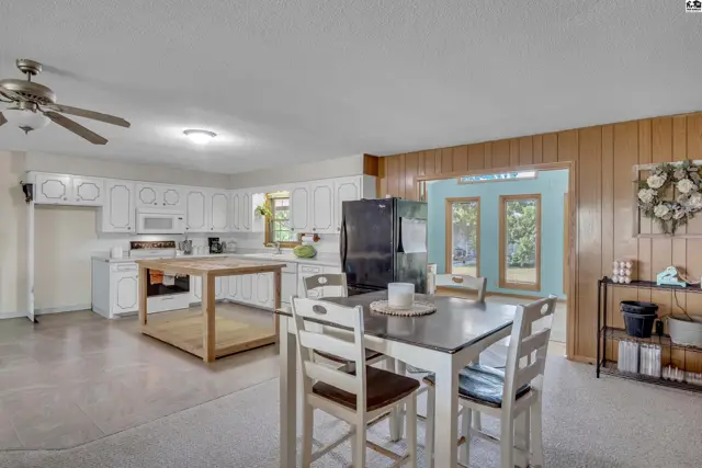 Spacious kitchen with white cabinetry, an island, and adjacent dining area.