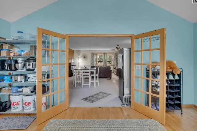 Open French doors reveal a dining area and living room with light blue walls.