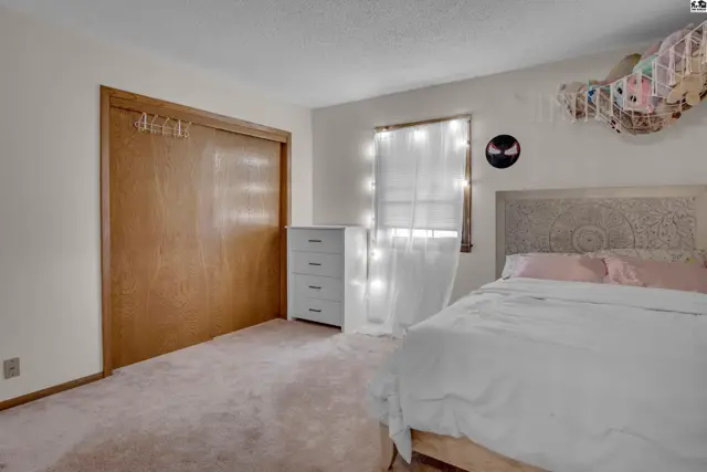 This bedroom features a large closet, a dresser, and a bed with a decorative headboard.
