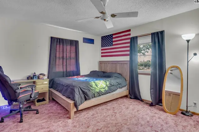 This bedroom features a queen-size bed, a desk, and a full-length mirror.