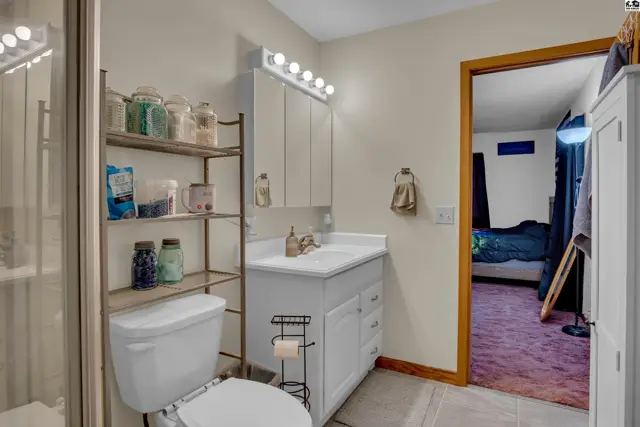 This bathroom features a white vanity, toilet, and a glass-enclosed shower.