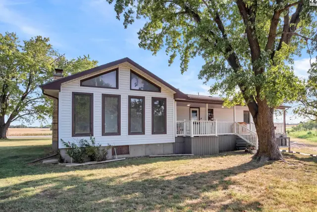 White-sided home with a peaked roof, large windows, and a wrap-around deck.