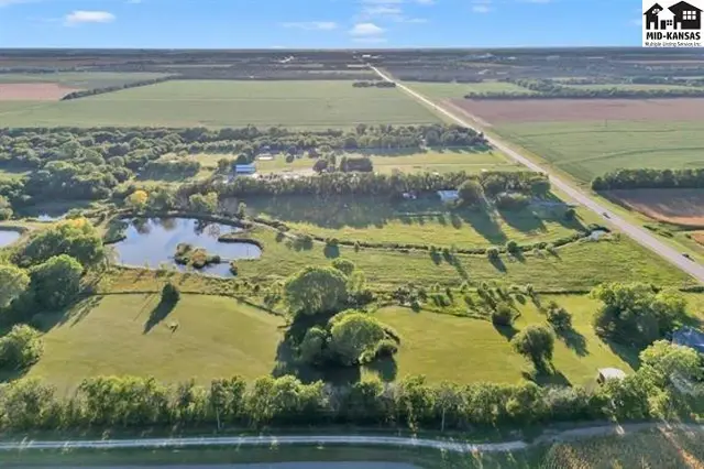 Expansive rural property features a pond, mature trees, and open fields.