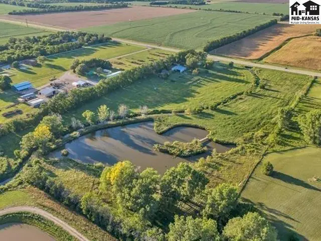 Expansive rural property features a large pond and mature trees surrounding a home.