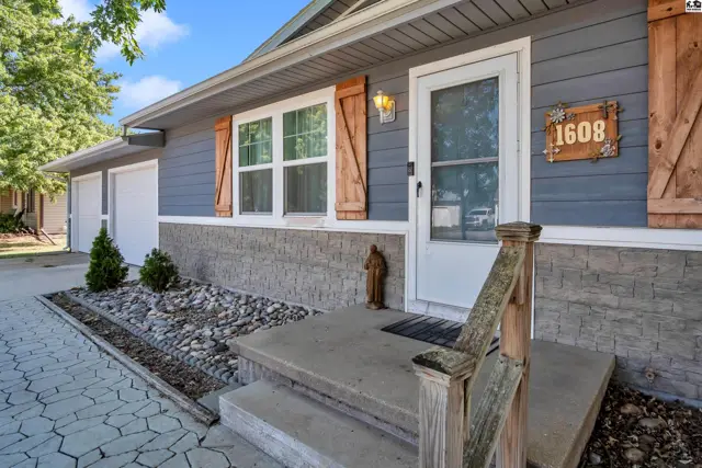 Blue siding and stone accent the front entrance with a concrete walkway and porch.