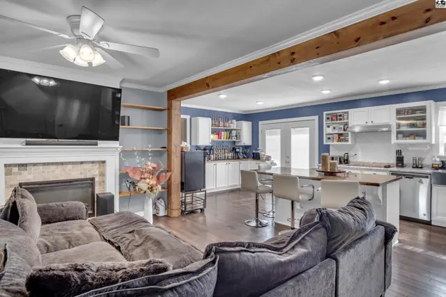 Spacious living area with fireplace opens to a bright kitchen with island seating.