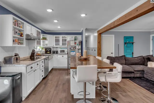 White cabinetry, a large island with seating, and stainless steel appliances define this spacious kitchen.