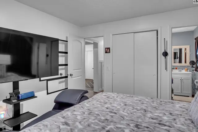 This bedroom features a large television, built-in shelving, and access to a bathroom.