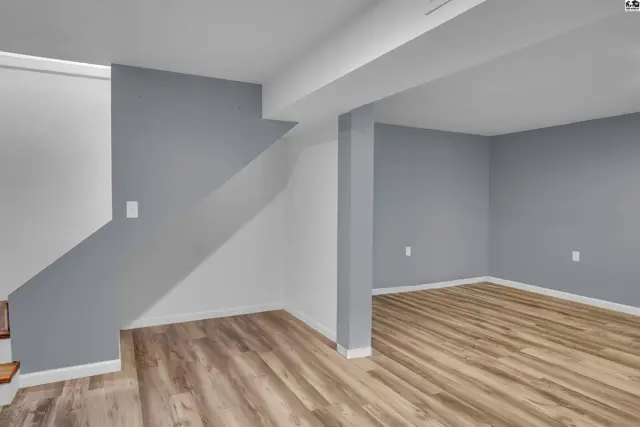 Finished basement with wood-look flooring and painted walls.