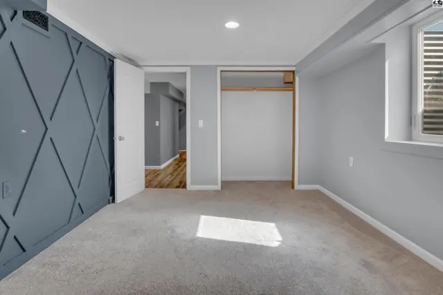 This room features grey walls, a closet, and a large window with blinds.