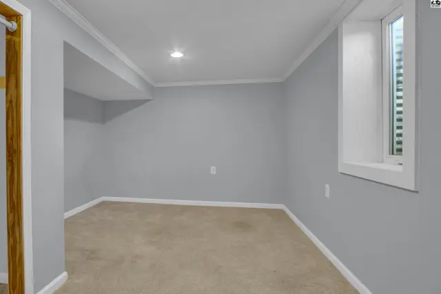 This room features light grey walls, a beige carpet, and a small window.