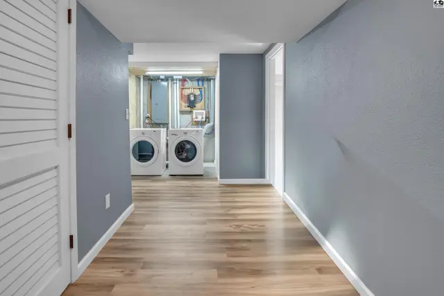 This laundry room features light wood-look flooring and light blue walls.