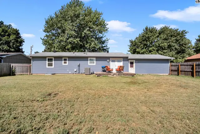 This single-story home features a blue exterior, a wooden deck, and a large grassy yard.