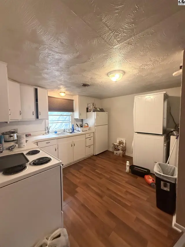 White cabinets and appliances fill this kitchen with wood-look flooring.