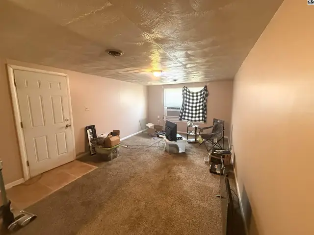 Carpeted room with a door, window, and air conditioning unit.